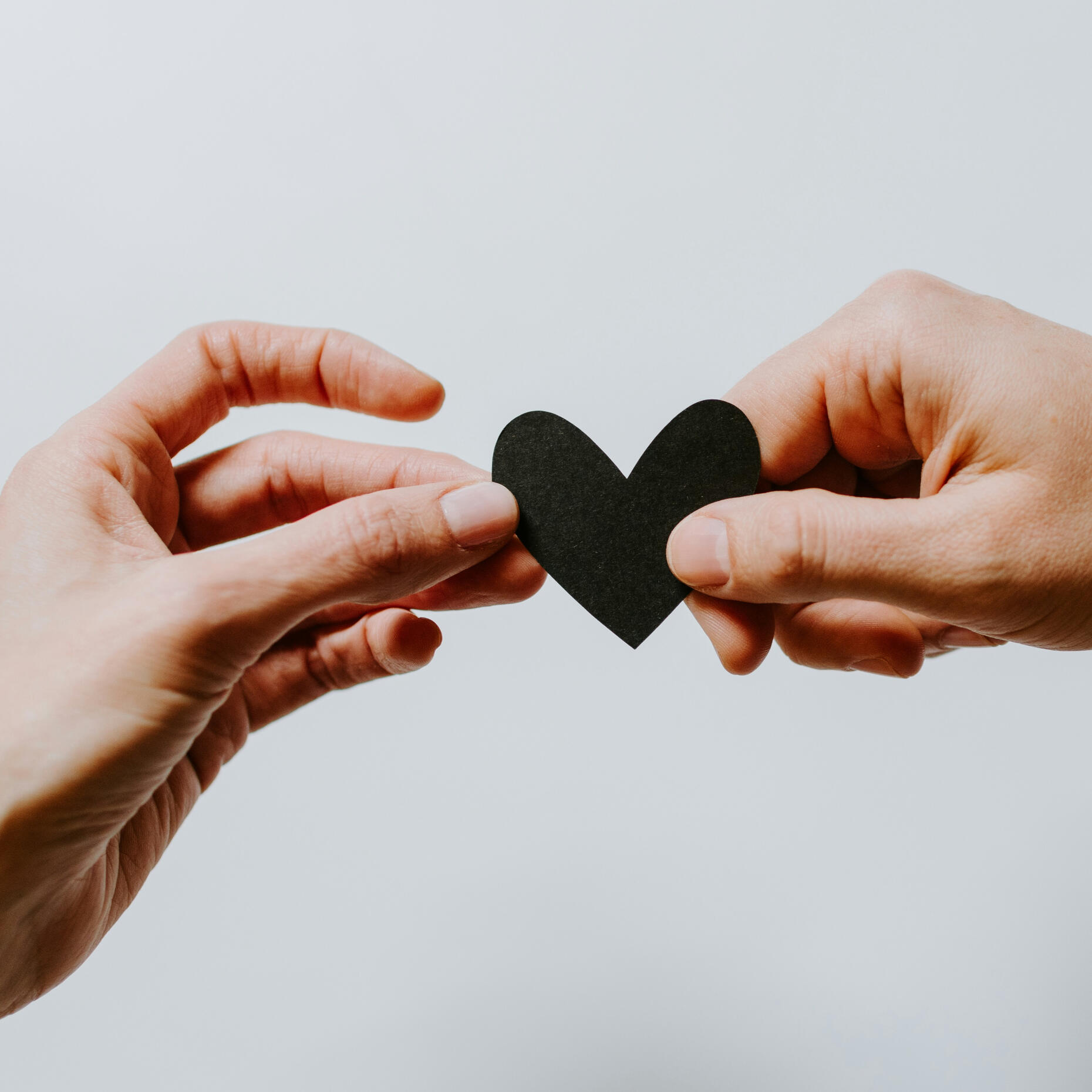 Two hands holding a heart shape, representing compassion, care and support for helping professionals